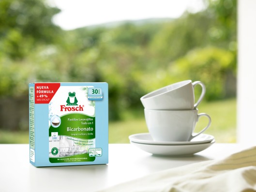 A pack of Frosch All-in-1 dishwasher tabs stands next to two stacked cups on a table	