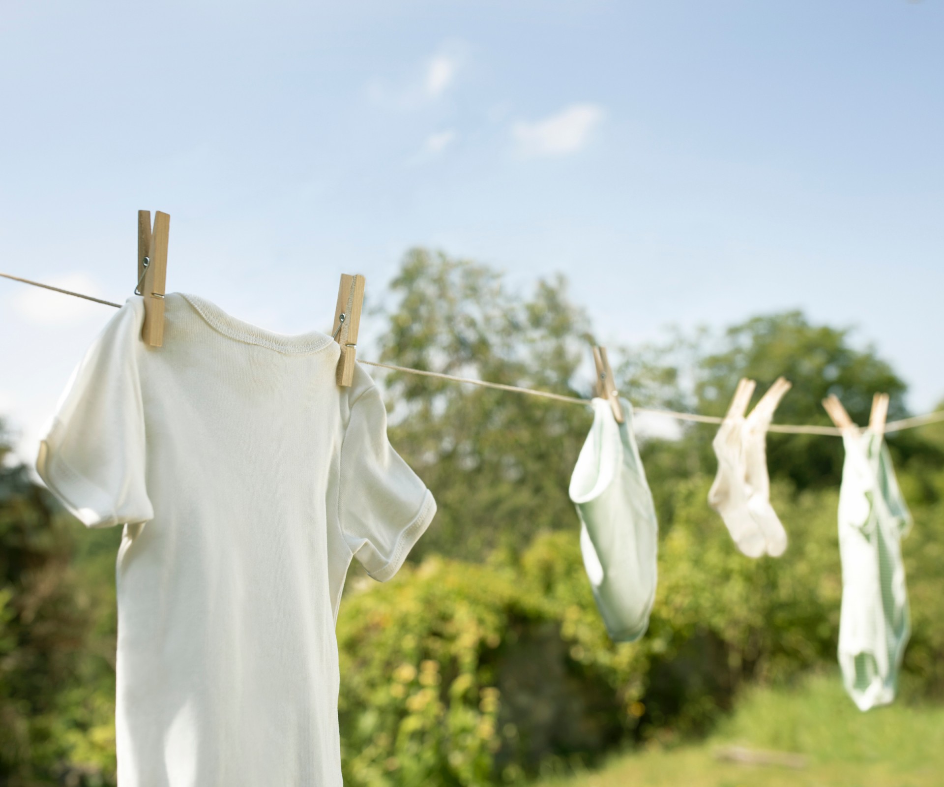 White clothes hang on a clothesline outside under blue sky	